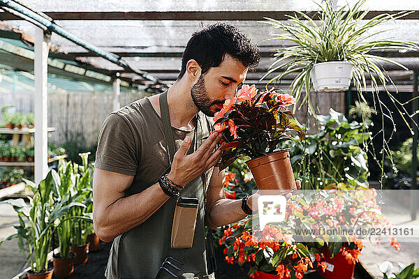 Worker in a garden center smelling at a flower