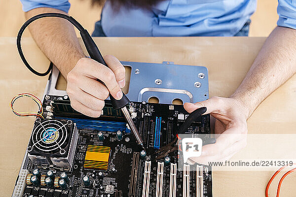 Close-up of technician repairing a desktop computer  soldering a component with tin
