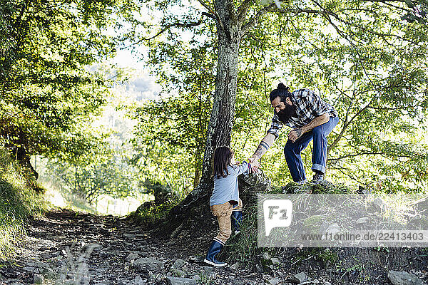 Boy reaching out for father s hand in the forest