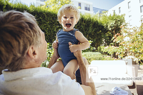 Father sitting in garden  playing with his little son