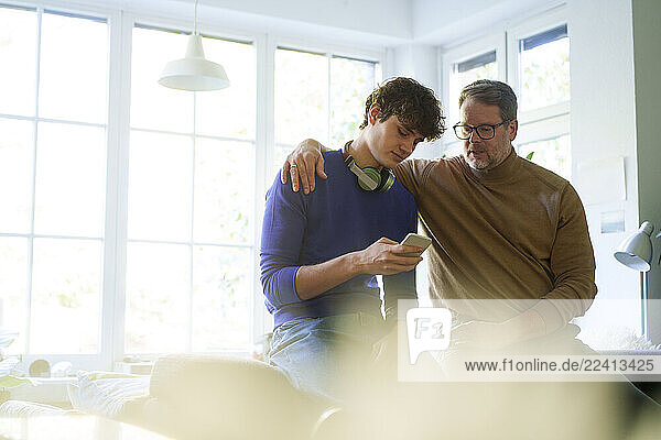 Father and son bonding at home while using a smartphone