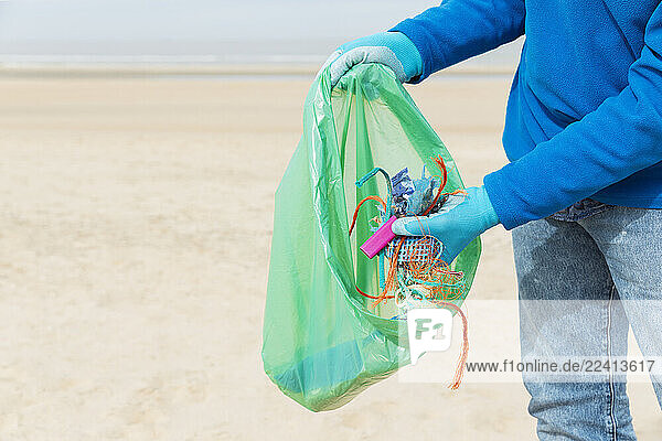 Man collecting ocean waste during a beach cleanup at the North Sea