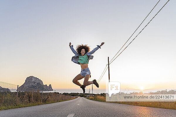 Young woman jumping on street at sunset  Ibiza