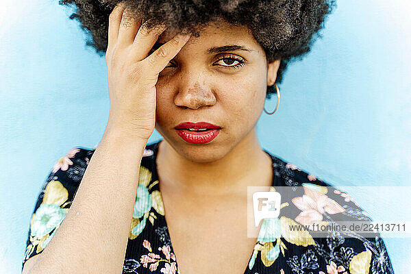 Portrait of Afro-American woman  hand on forehead  blue wall in the background