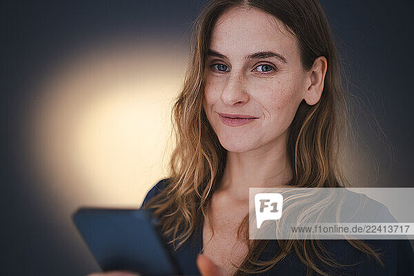 Confident woman using smartphone indoors