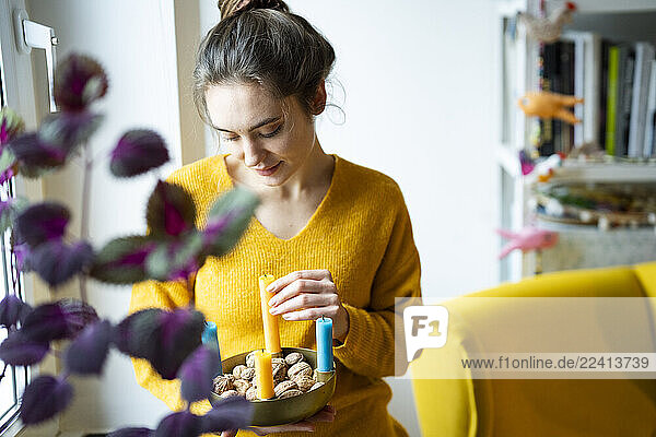 Woman in yellow sweater enjoying a tranquil moment at home with tea and candles