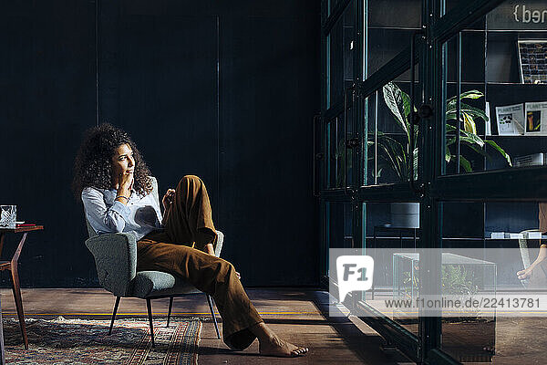 Young businesswoman looking out of window in loft office