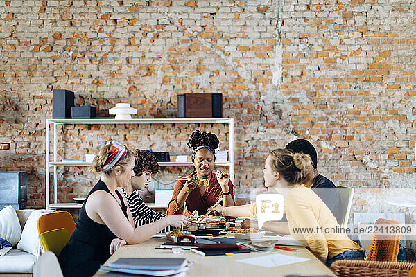 Young people sitting together at table having lunch break