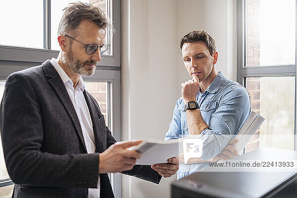 Two men in an office discussing business documents during a meeting