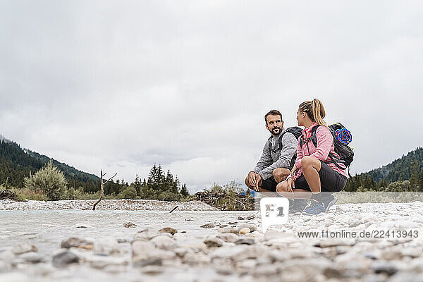 Young couple on a hiking trip crouching at riverside  Vorderriss  Bavaria  Germany