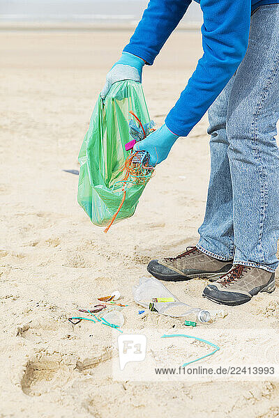 Man collecting plastic waste during a beach cleanup on the North Sea coast