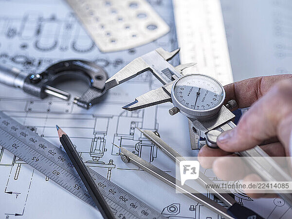 Close-up of engineering tools and calipers on a technical drawing for precision measurement