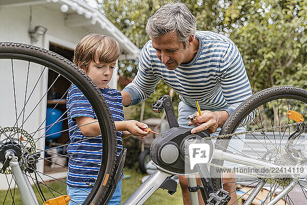 Father and son repairing a bicycle in garden