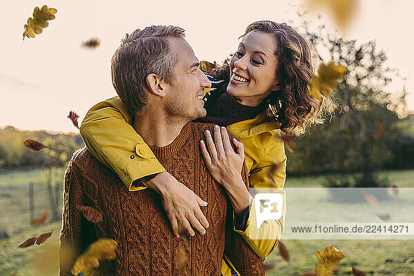 Man giving woman a piggyback ride outdoors in autumn