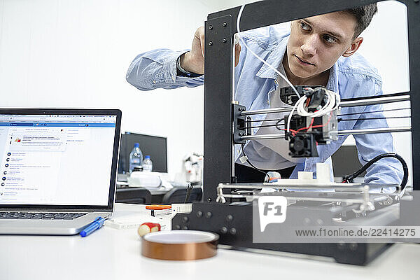 Student setting up 3D printer  using laptop