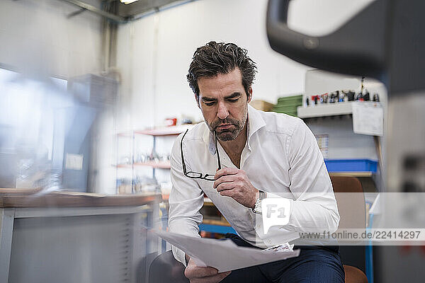 Businessman reading paper in a factory