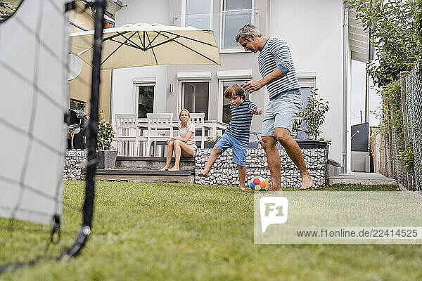 Father and son playing football in garden
