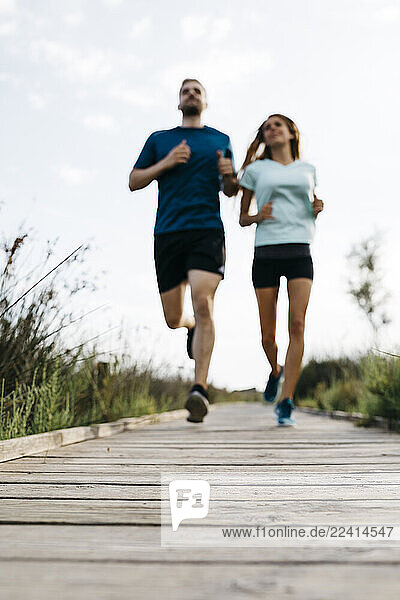 Young couple jogging on wooden walkway  blurred