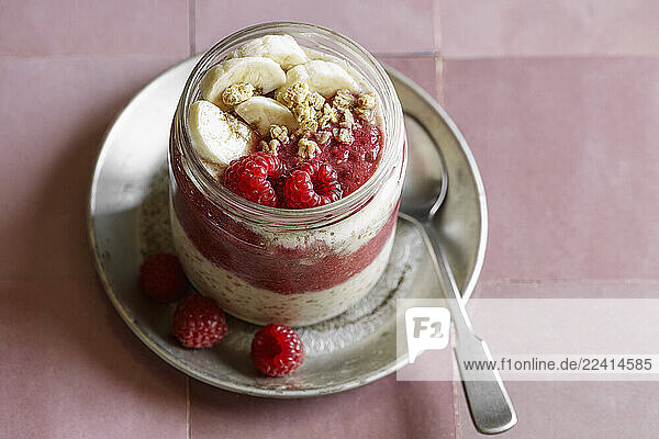 Vegan raspberry-banana overnight oats in a glass jar with granola