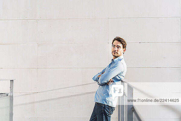 Portrait of confident casual businessman leaning against a railing