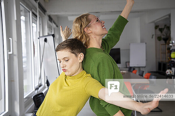 Two women in an office setting joyfully posing for a selfie