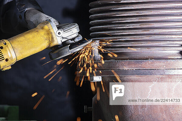 Close-up of worker using angle grinder in a factory