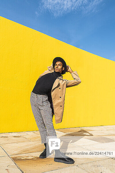 Young man dancing in front of yellow wall