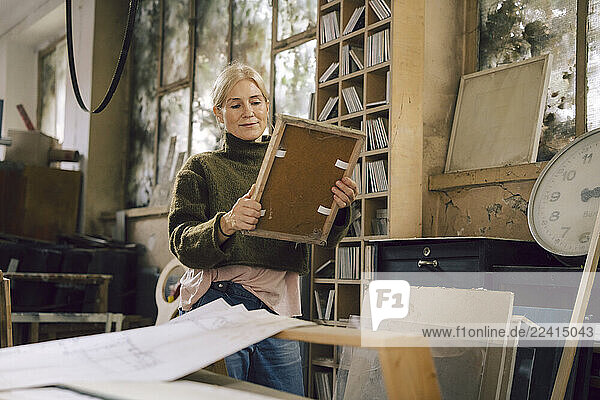 Small business owner in a workshop examining a frame with passion and skill