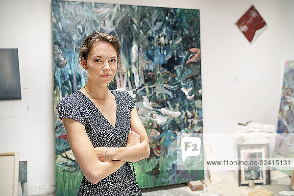 Young artist standing in her studio  with arms crossed