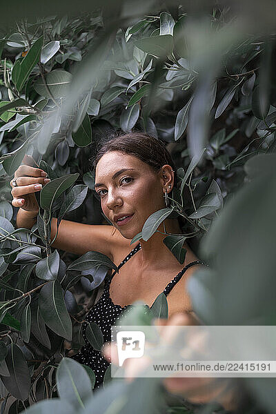 Portrait of young woman among green leaves