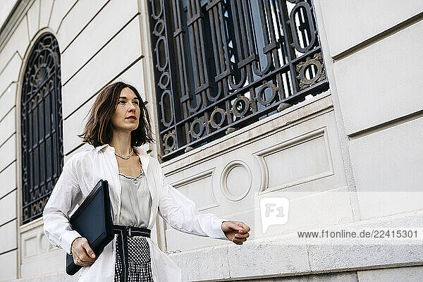 Well dressed woman carrying folder  walking in the city