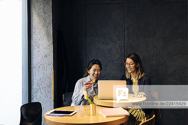 Colleagues discussing work  using laptop  drinking after work cocktails