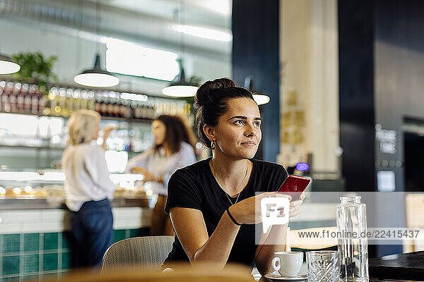 Young woman sitting in bistro  using smartphone