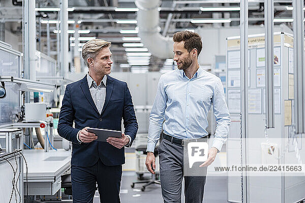Two businessmen with tablet talking in a modern factory