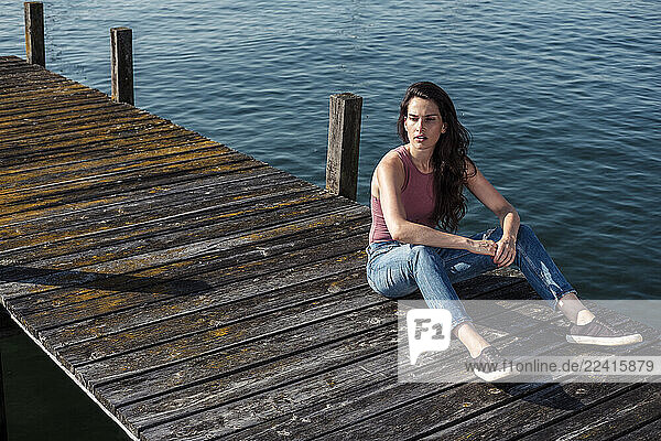 Young woman sitting on jetty looking at distance  Lake Starnberg  Germany