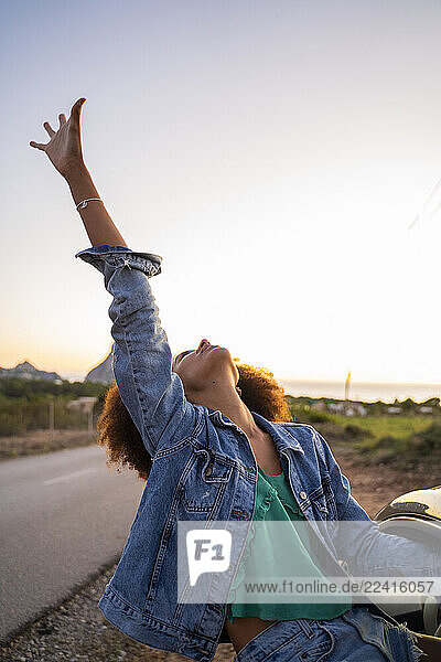 Young woman during road trip with raised arm