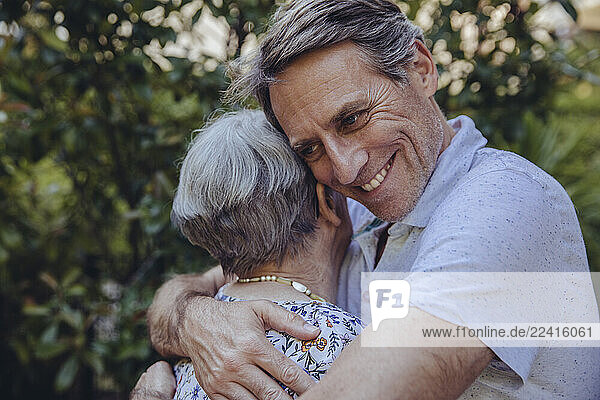 Adult son embracing his mother in the garden