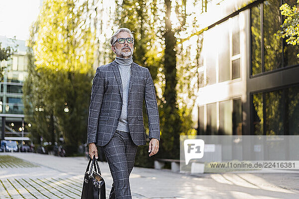 Fashionable mature businessman with bag on the go in the city