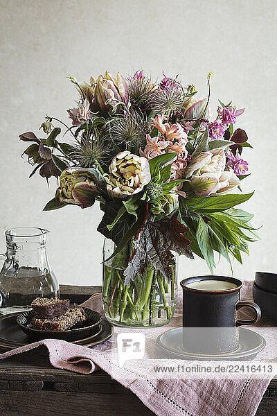 Studio shot a cut flowers bouquet with coffee and cake