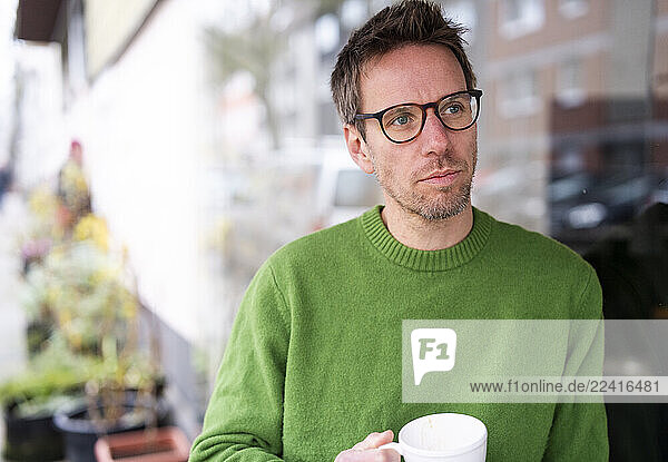 Businessman enjoying coffee at a café while working remotely on a sunny day