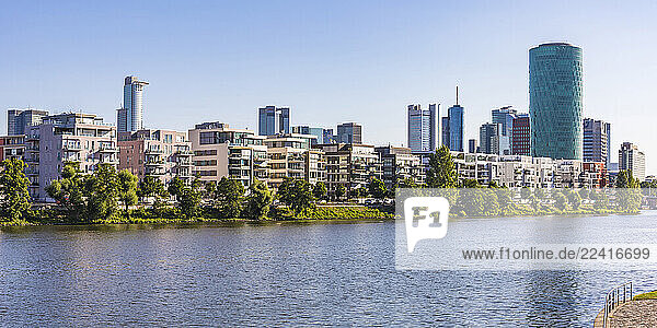 Residential buildings and Westhafen Tower by river against clear sky in Frankfurt  Germany