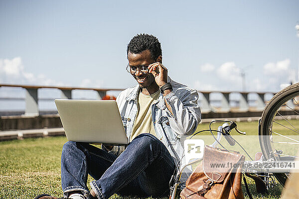 Young man sitting on grass  using laptop
