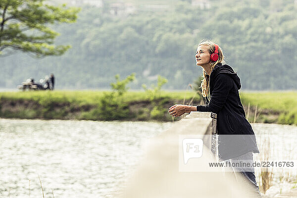 Young woman with red headphones relaxing at Lake Idro  Baitoni  Italy