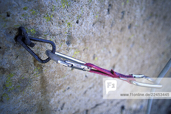 A quick draw hangs from an old bolt on a climbing route.