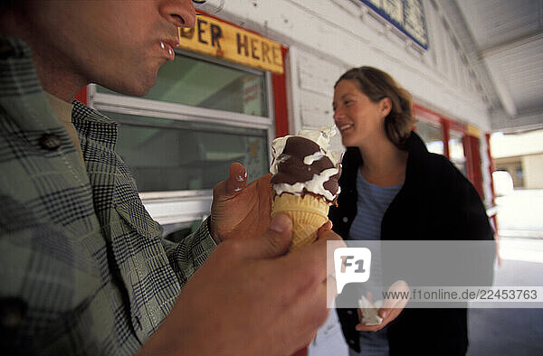 A man and woman enjoy chocolate-dipped soft serve.