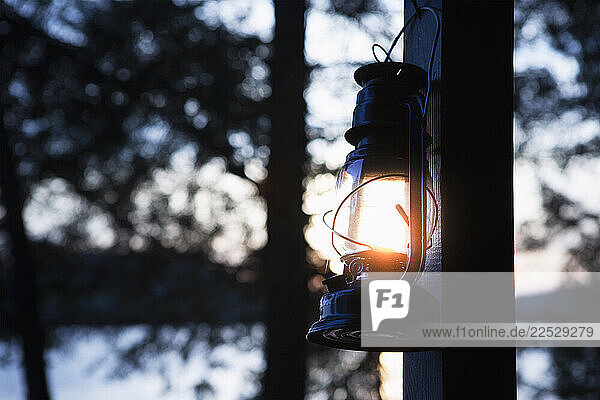 Kerosene lantern hanging by lakeside camp at sunset