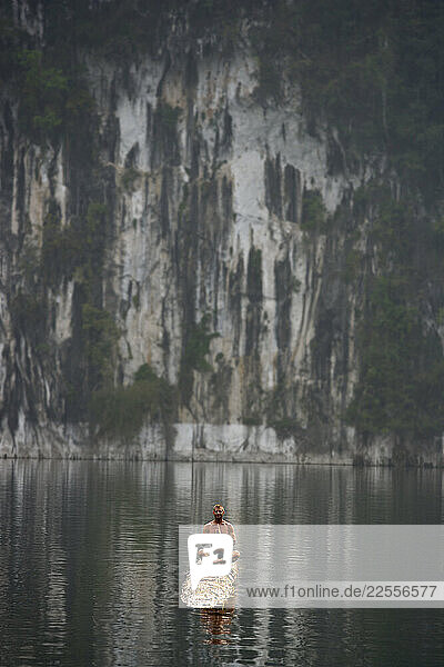 Oliver Reinsch and Alicia Cheung practice couples yoga on a log floating on a a lake in Khao Sok National Park  Southern Thailand
