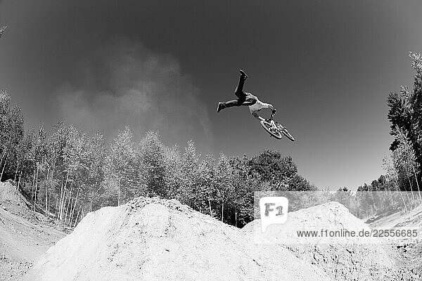 Mountain biker Dave Smutok hits a dirt jump and pulls an Indian Air trick while in midair.