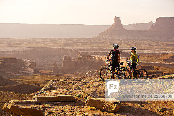 Mountain bikers Brad Barlage and Katie Caviccio take a break and watch the sun setting over Canyonlands National Park while mountain biking the White Rim Trail in Southern Utah.