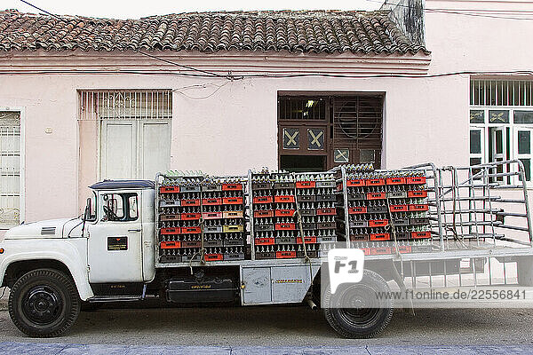 A work truck stocked full of recycling bottles sits outside a shop in Santa Clara  Cuba.